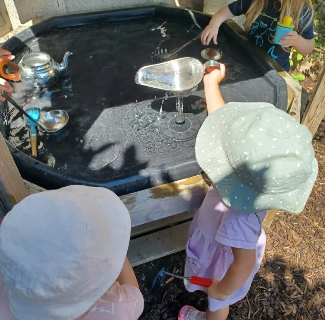 Children enjoying water play in the garden on a sunny day