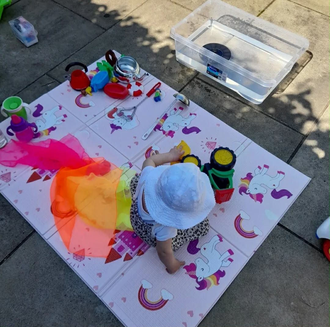 Baby playing with toys on a soft mat outdoors