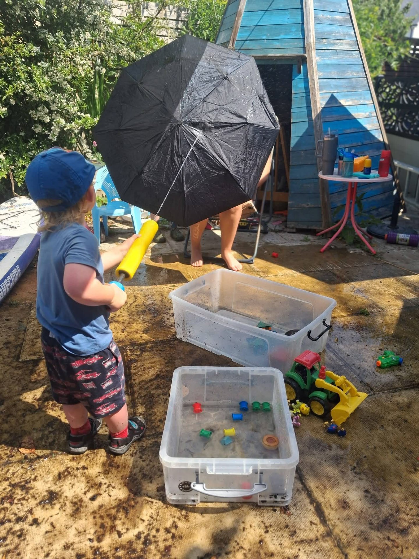 Child playing with water and an umbrella in the garden