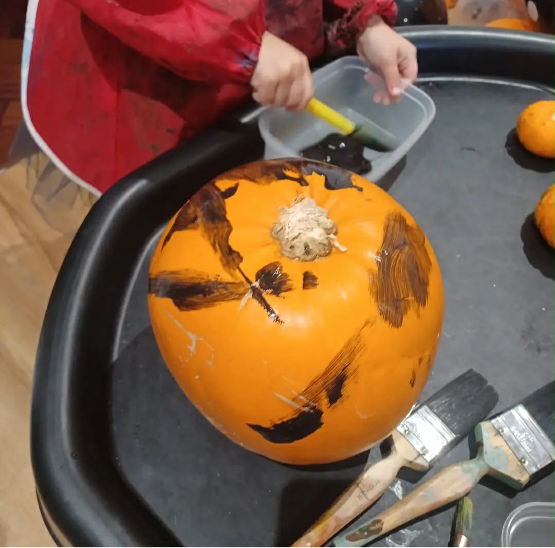 Toddler painting a pumpkin in the tuff tray
