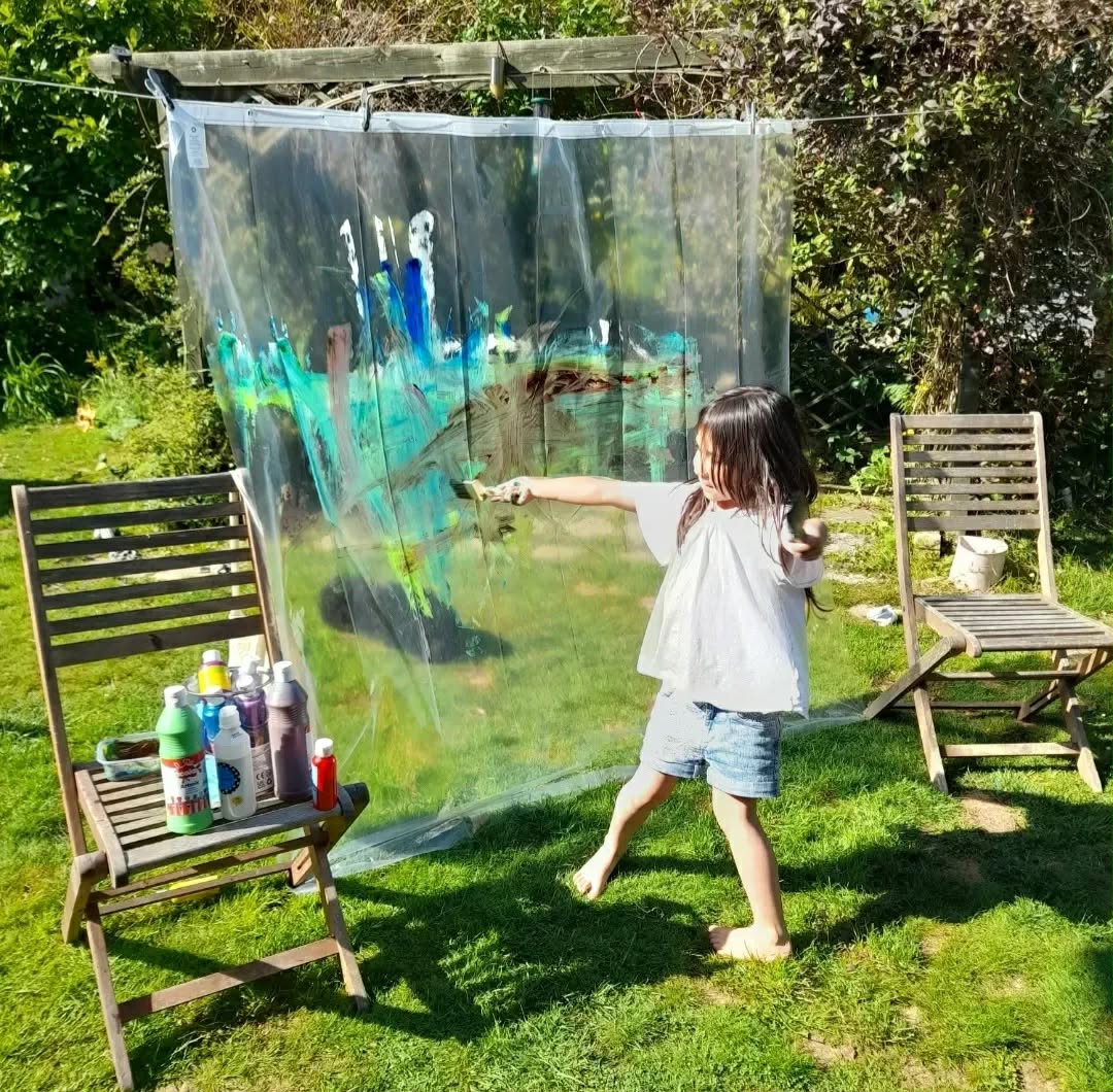 Child painting on a large outdoor painting screen in the garden